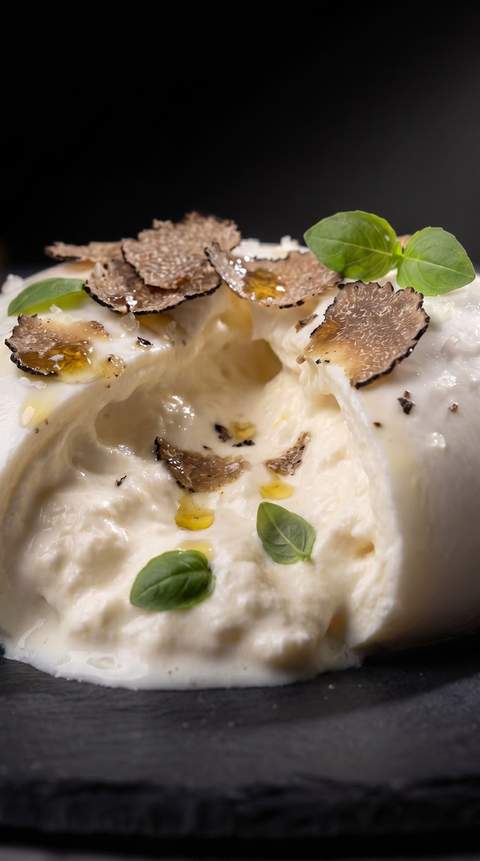 The same mozzarella plated with black truffle on dark slate